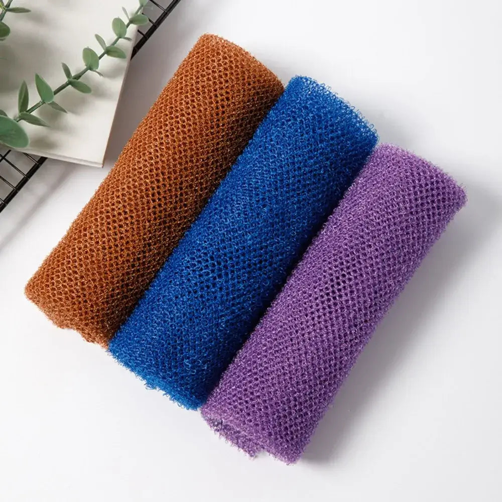 Three colorful exfoliating mesh sponges in brown, blue, and purple stacked together on a white background.